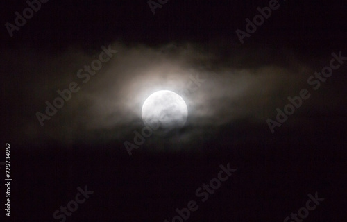 The moon in the haze of the clouds at night