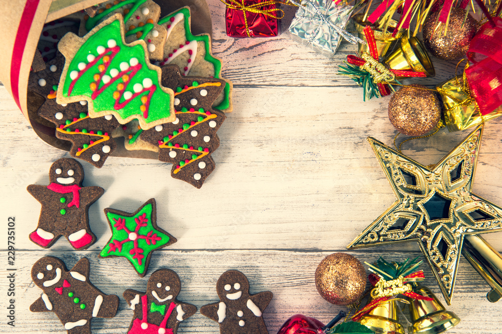Fototapeta premium Beautiful Christmas composition and decoration with baked Christmas gingerbread cookies in paper bag on light wooden background, flat lay, top view, copy space (text space)