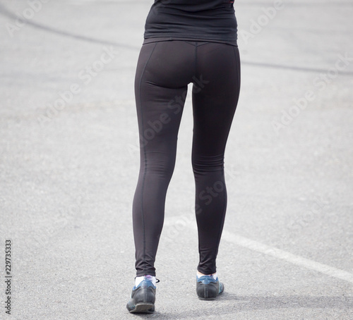Legs of a girl in black pantyhose walking along the road