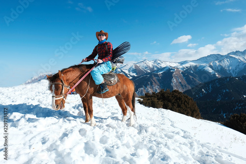 Freeride on horseback. A man in a cowboy hat riding a horse in the snow. Winter. the mountains.