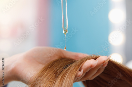 Close-up drop of oil restore and recovery hair is applied to head bulbs. hairdresser spa salon. photo