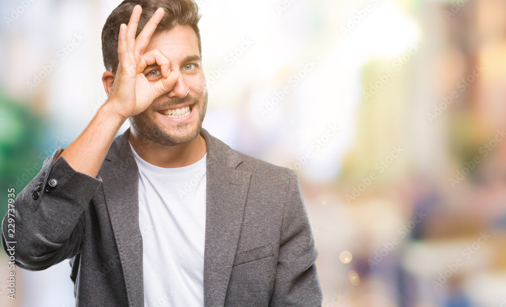 Obraz premium Young handsome business man over isolated background doing ok gesture with hand smiling, eye looking through fingers with happy face.