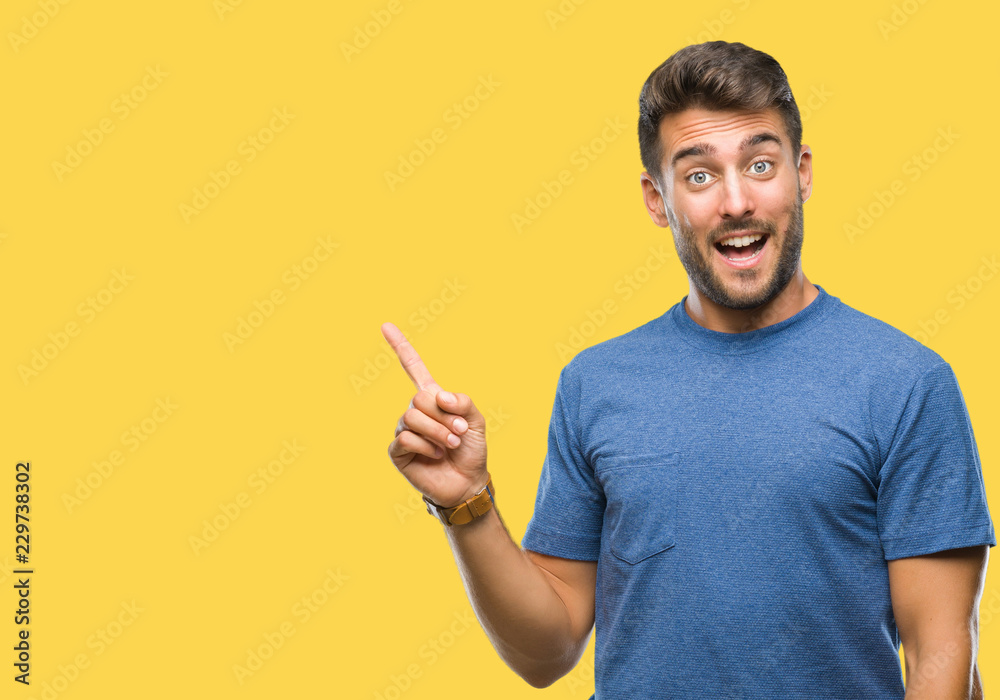 Young handsome man over isolated background with a big smile on face, pointing with hand and finger to the side looking at the camera. Young handsome man over isolated background with a big smile on face, pointing with hand and finger to the side looking at the camera.