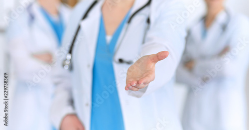 Group of medicine doctors offering helping hand for shaking hand or saving life closeup. Partnership and trust concept in health care or medical cure 