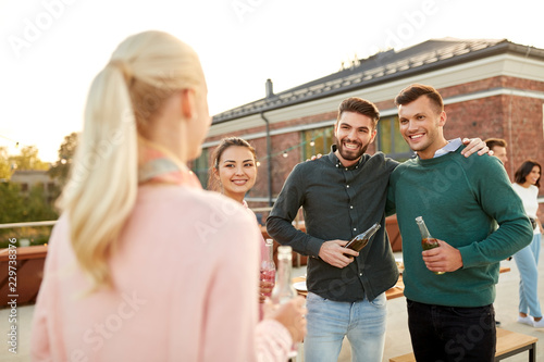 leisure and people concept - happy friends with drinks hugging at rooftop party