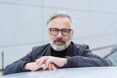 Man leaning on his car looking at the camera