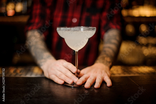 Barman holding a fresh Margarita cocktail in a cocktail glass