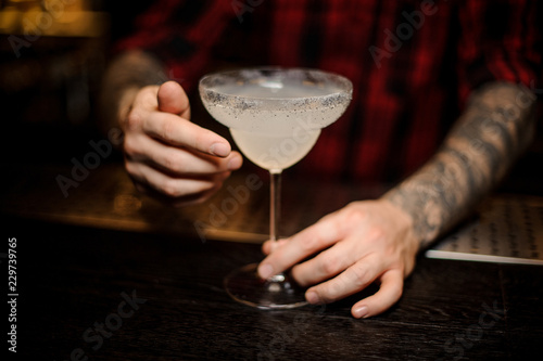 Bartender holding a fresh Margarita cocktail in a cocktail glass