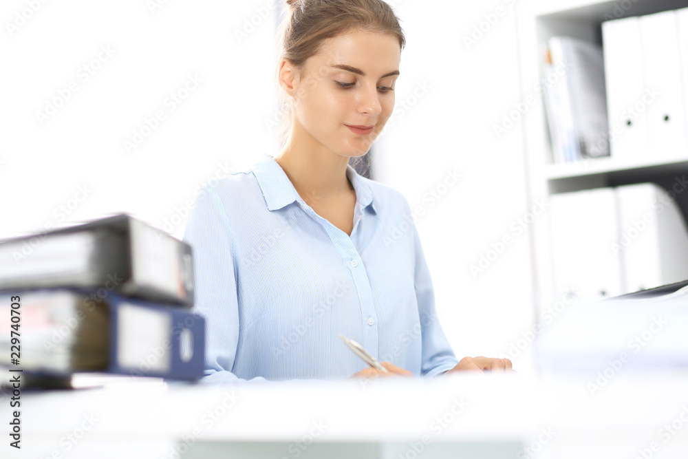 Woman bookkeeper or financial inspector calculating or checking balance, making report. Internal Revenue Service at work with financial document. Tax and audit concept Woman bookkeeper or financial inspector calculating or checking balance, making report. Internal Revenue Service at work with financial document. Tax and audit concept