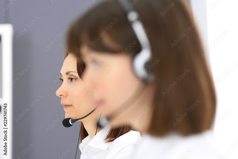 Call center. Group of operators at work. Focus on young brunette woman. Business concept Call center. Group of operators at work. Focus on young brunette woman. Business concept