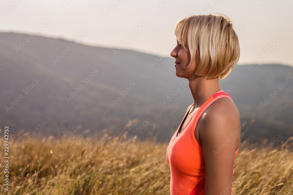 Fitness woman enjoys relaxing in the nature after exercise.