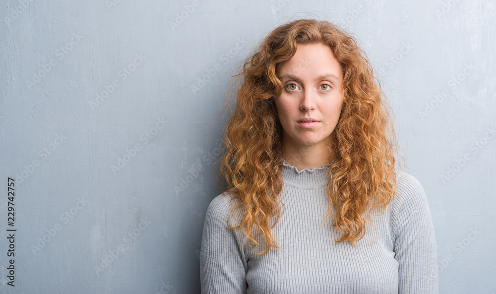 Young redhead woman over grey grunge wall with a confident expression on smart face thinking serious Young redhead woman over grey grunge wall with a confident expression on smart face thinking serious
