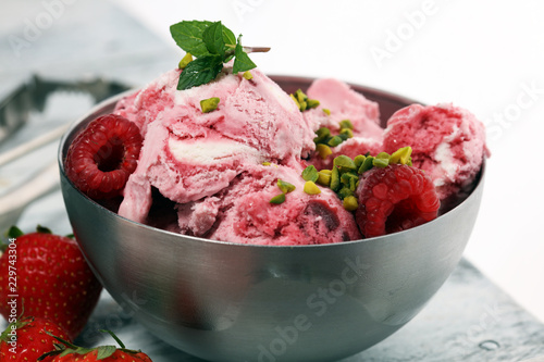 Strawberry and raspberry ice cream scoop with chopped nuts and white chocolate on a rustic background