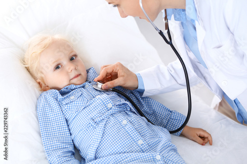 Doctor examining a little blonde girl with stethoscope.Medicine and healthcare concept