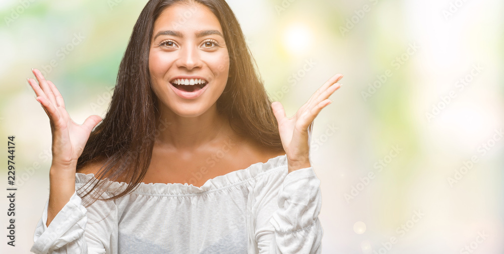 Young beautiful arab woman over isolated background celebrating crazy and amazed for success with arms raised and open eyes screaming excited. Winner concept Young beautiful arab woman over isolated background celebrating crazy and amazed for success with arms raised and open eyes screaming excited. Winner concept
