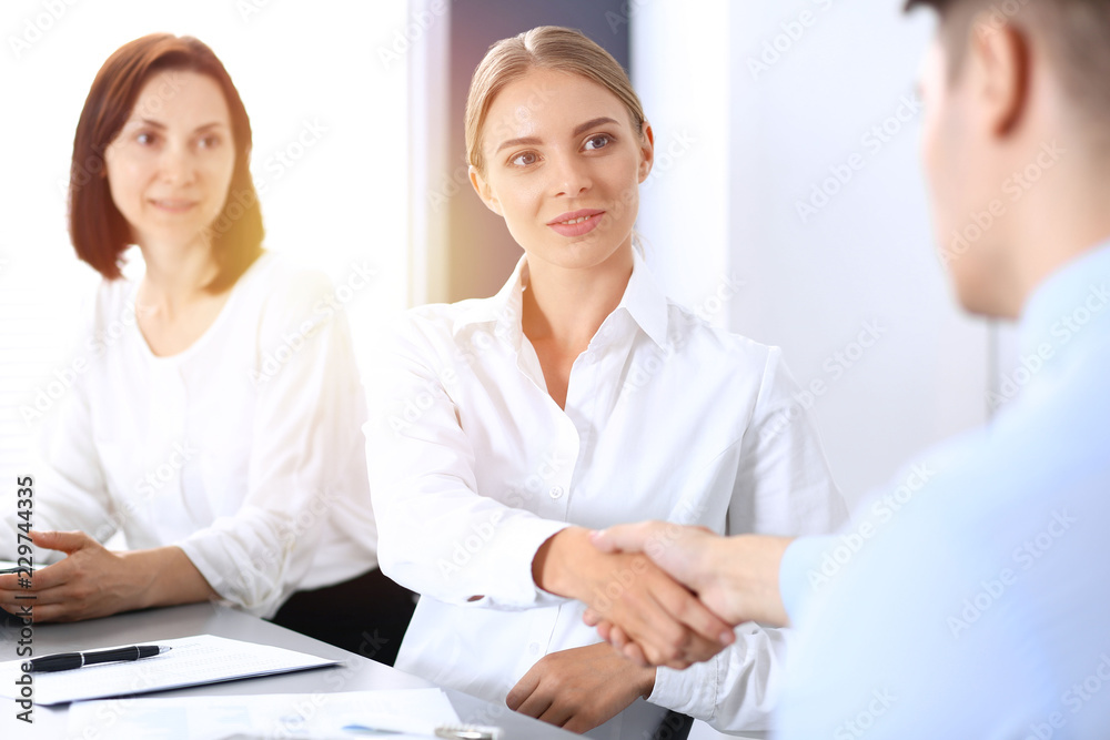 Business handshake by blonde woman and her partner at meeting. Concept of success and agreement Business handshake by blonde woman and her partner at meeting. Concept of success and agreement