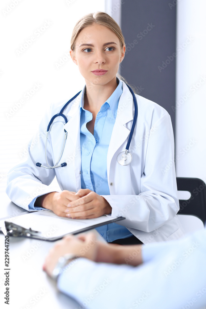 Doctor and patient in hospital. Beautiful blonde physician consulting business man about his health. Medicine concept Doctor and patient in hospital. Beautiful blonde physician consulting business man about his health. Medicine concept