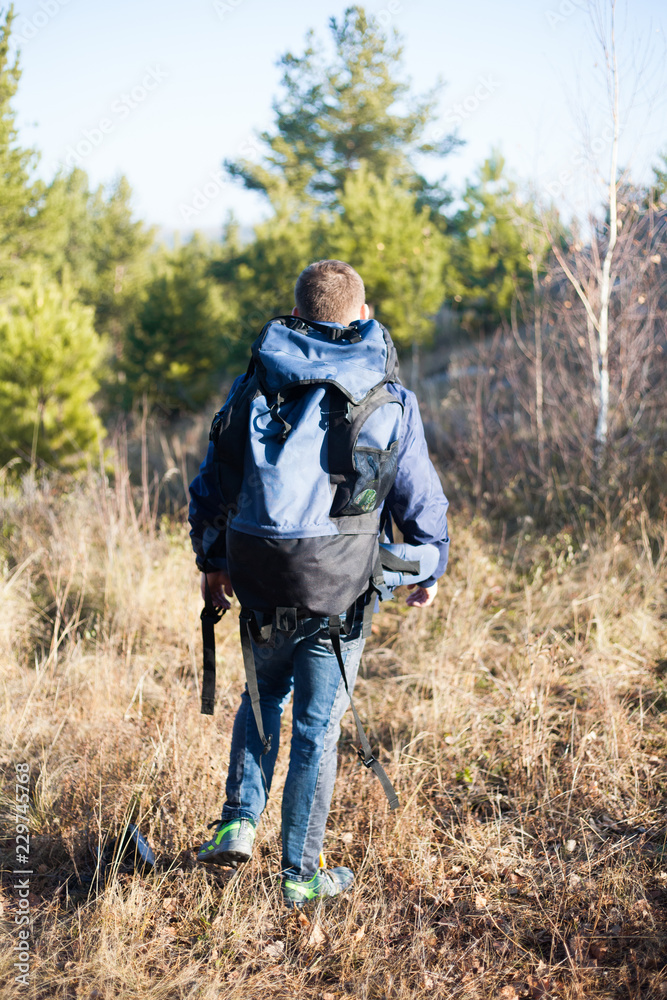 handsome man guy tourist standing alone by the mountain forest landscape during his summer vacation with his backpack back view handsome man guy tourist standing alone by the mountain forest landscape during his summer vacation with his backpack back view