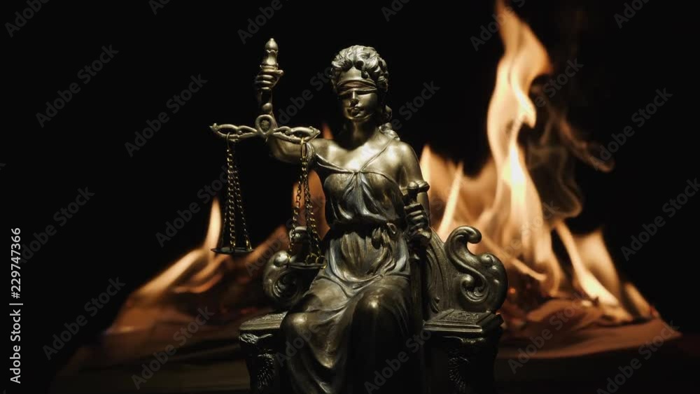 Statue of Lady Justice on the background of the flame of a burning book Statue of Lady Justice on the background of the flame of a burning book