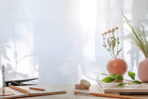 Fototapeta Naklejka Na Ścianę i Meble -  Hipster wooden desk with vases with dried plants, open notebook and brush set under the window
