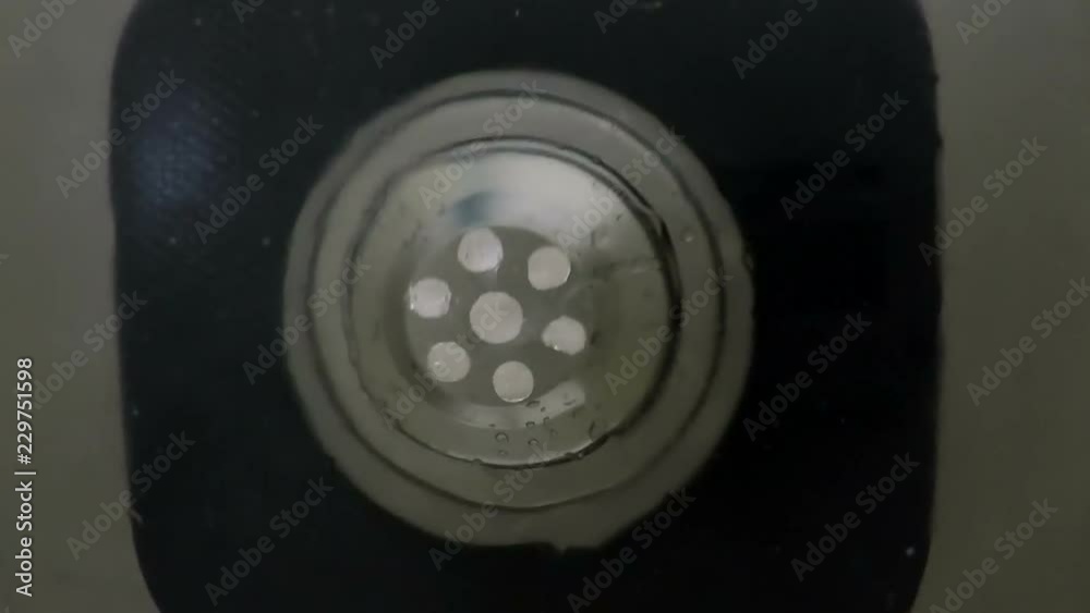 Bottom view through the sink drain with water flowing down Bottom view through the sink drain with water flowing down