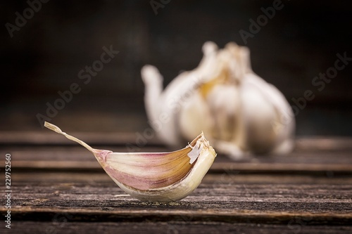 A single garlic clove in front of a bulb of garlic photo