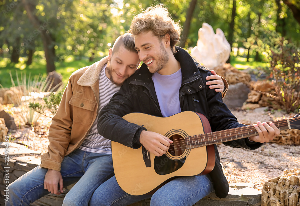 Happy gay couple with guitar in park Stock Photo | Adobe Stock