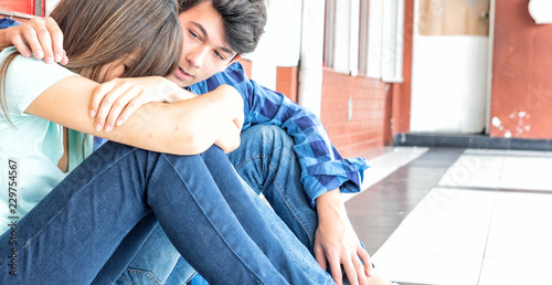 Teenagers couple at school. Boy conforting sad girl photo