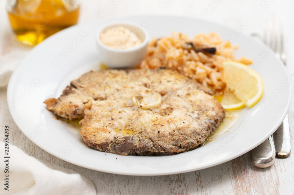 fried fish with rice and lemon on white plate