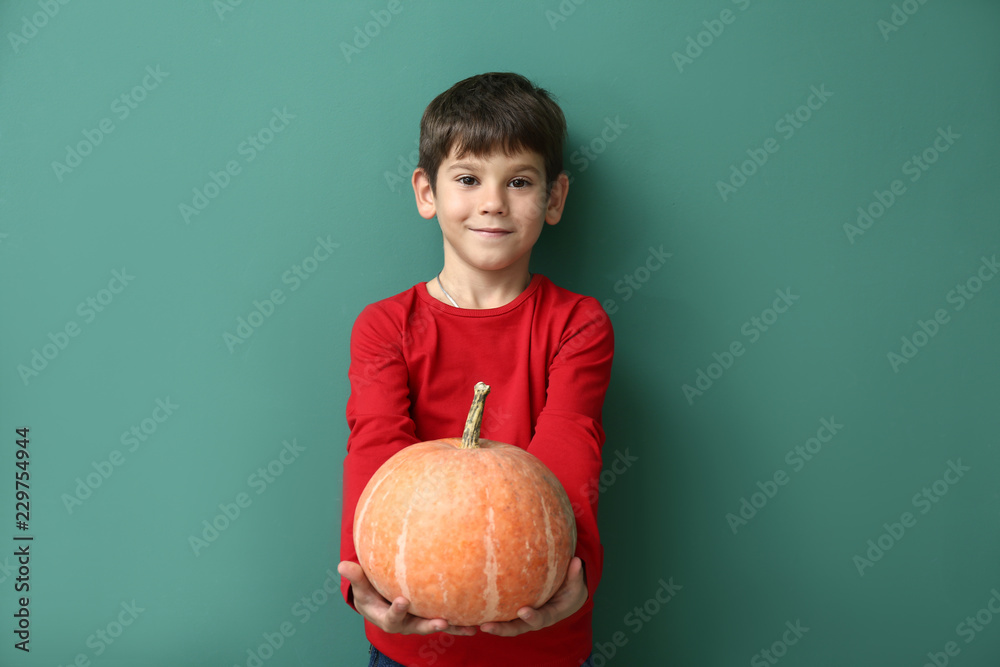Fototapeta premium Cute little boy with pumpkin on color background