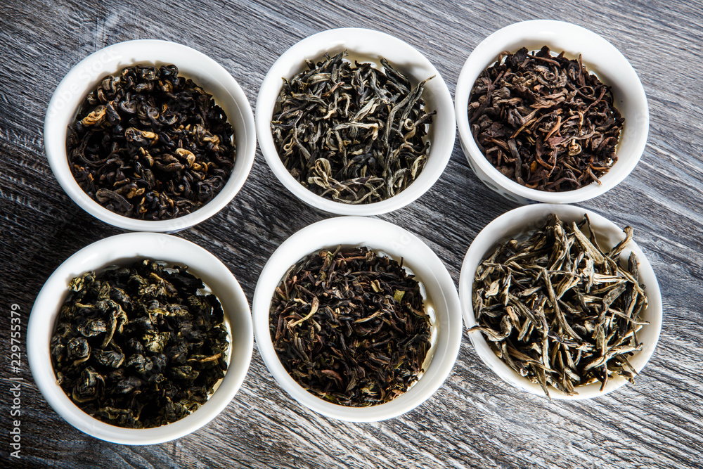 closeup assorted tea leaves in six white small round vessels closeup assorted tea leaves in six white small round vessels
