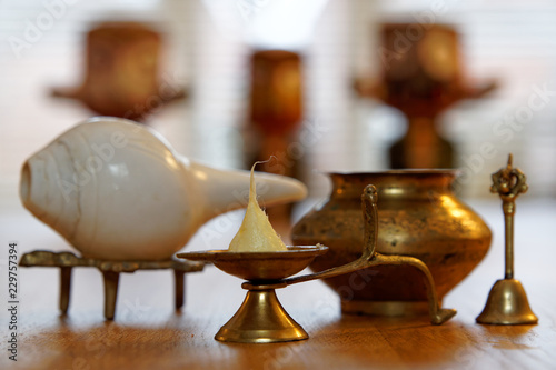 Ghee candle, conch shell with brass bell and water pot, Hindu deity Lord Jagannath in the blurry background
