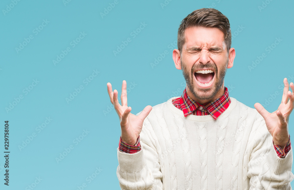 Fototapeta premium Young handsome man wearing winter sweater over isolated background celebrating mad and crazy for success with arms raised and closed eyes screaming excited. Winner concept