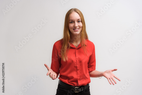 Studio portrait on the camera of a smiling beautiful girl with long hair talking on a white background with emotions.