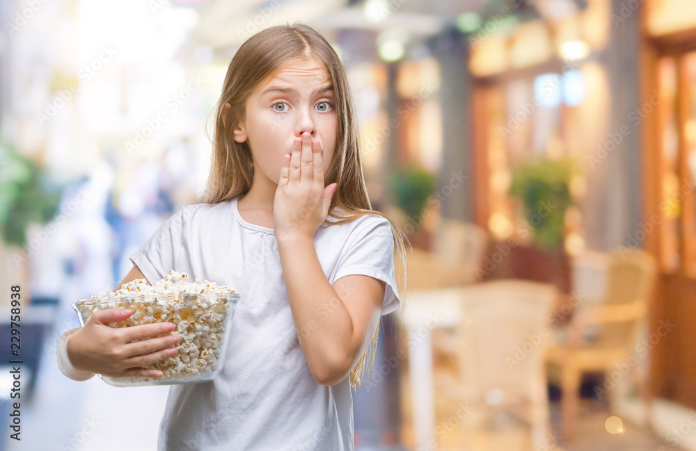 Young beautiful girl eating popcorn snack isolated background cover mouth with hand shocked with shame for mistake, expression of fear, scared in silence, secret concept