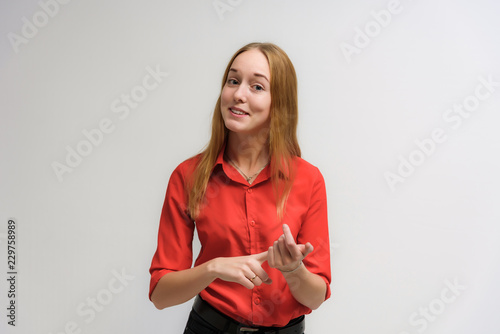 Studio portrait on the camera of a smiling beautiful girl with long hair talking on a white background with emotions.