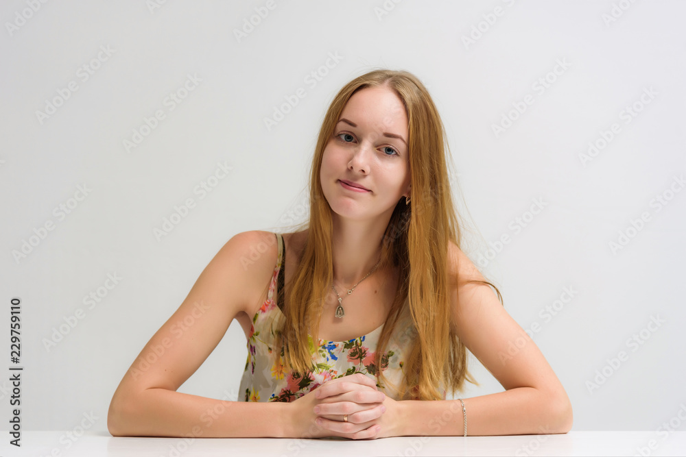 portrait on camera of a smiling beautiful girl is talking at a table on a white background.