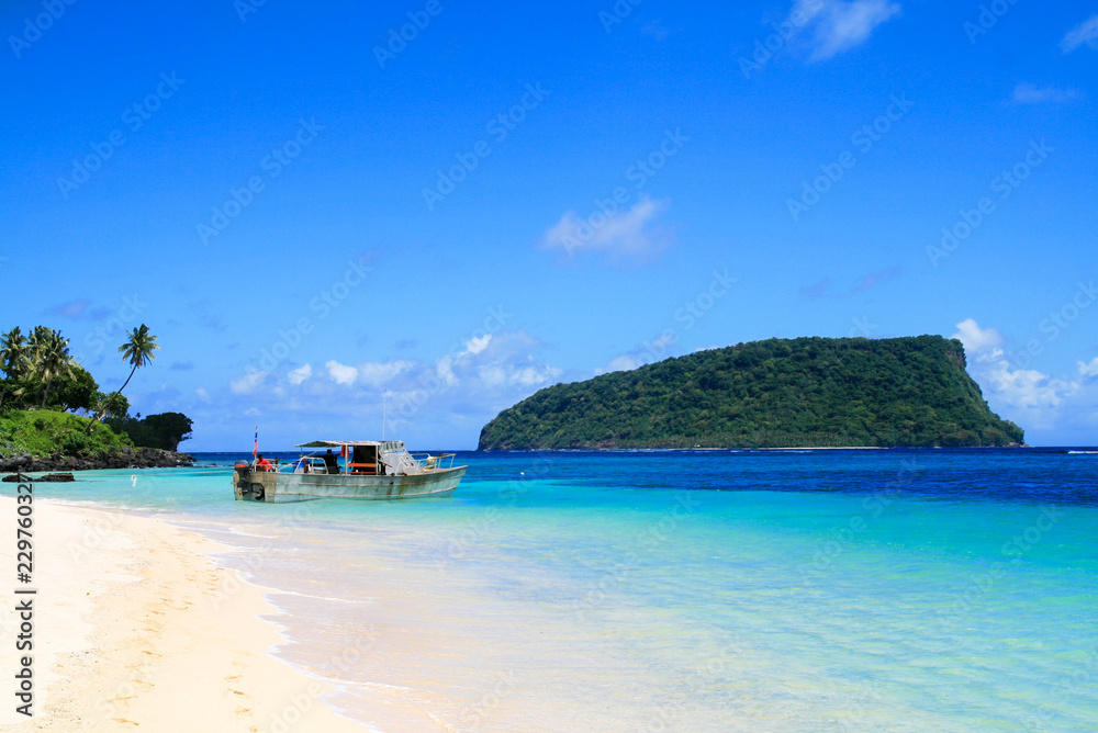 Polynesian fisherman boat dock on white golden sandy Lalomanu beach at tropical paradise in Pacific Ocean’s Upolu Island, turquoise coral waters with view of Nu’utele island