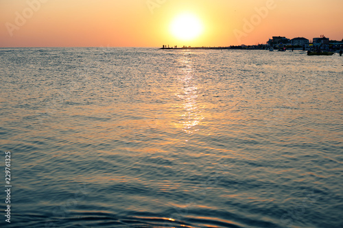 beautiful red sunset on the sea with sun reflection on the water and people standing on the pier