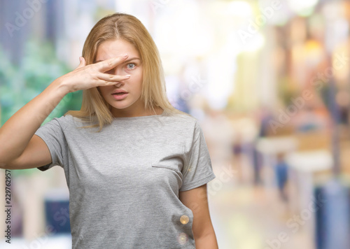 Fototapeta Naklejka Na Ścianę i Meble -  Young caucasian woman over isolated background peeking in shock covering face and eyes with hand, looking through fingers with embarrassed expression.