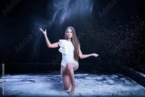 sporty young girl throws flour on black background