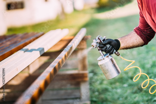 Industrial handyman, male construction worker painting with spray gun on site photo