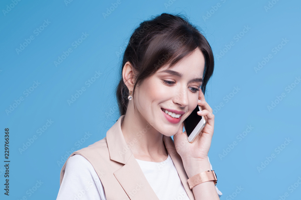 Beautiful successful young business woman uses phone on blue background Beautiful successful young business woman uses phone on blue background