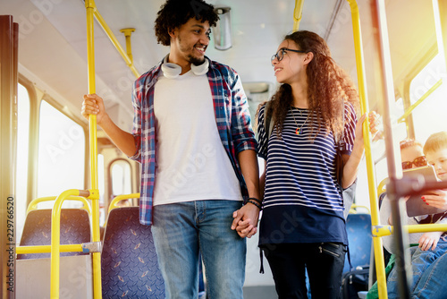 Happy young couple holding hands in a bus. Looking at each other.