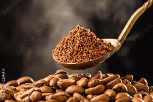 Roasting coffee beans into an old silver antique spoon on dark background. Smoke  steam of roasting coffee. morning fresh coffee aroma.