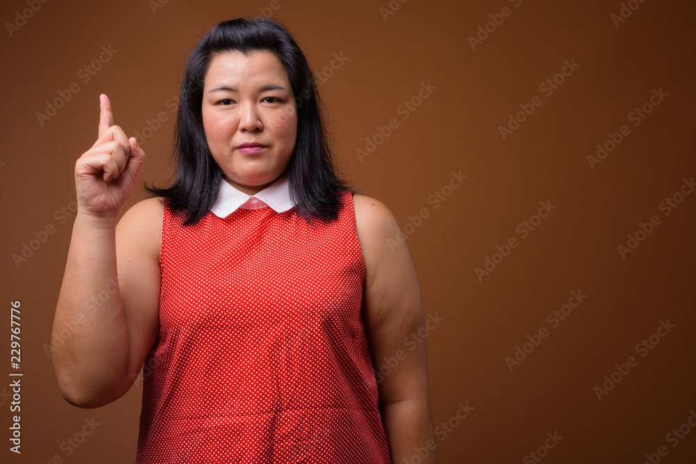 Beautiful overweight Asian woman pointing finger up Beautiful overweight Asian woman pointing finger up