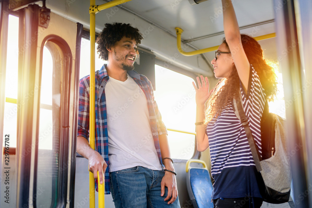 Young cute couple standing in a bus and talking. Mix race couple . Stock  Photo | Adobe Stock