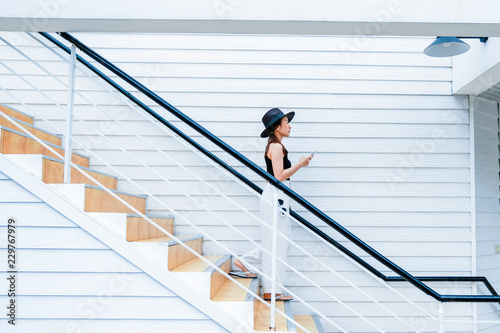 woman in holiday by walk down on stairway with hold mobile