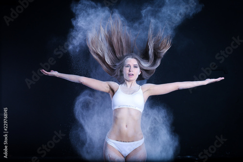 sporty young girl throws flour on black background