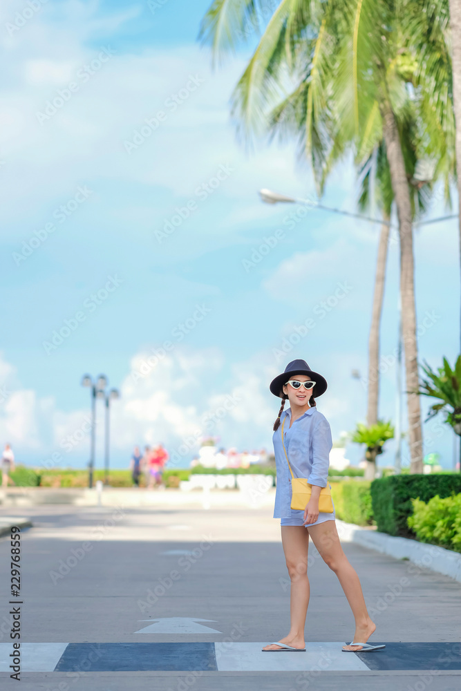 portrait beautiful woman in outdoor walkway with walking posing relax smile happy in holiday by wear hat and fashion sunglasses and bag yellow